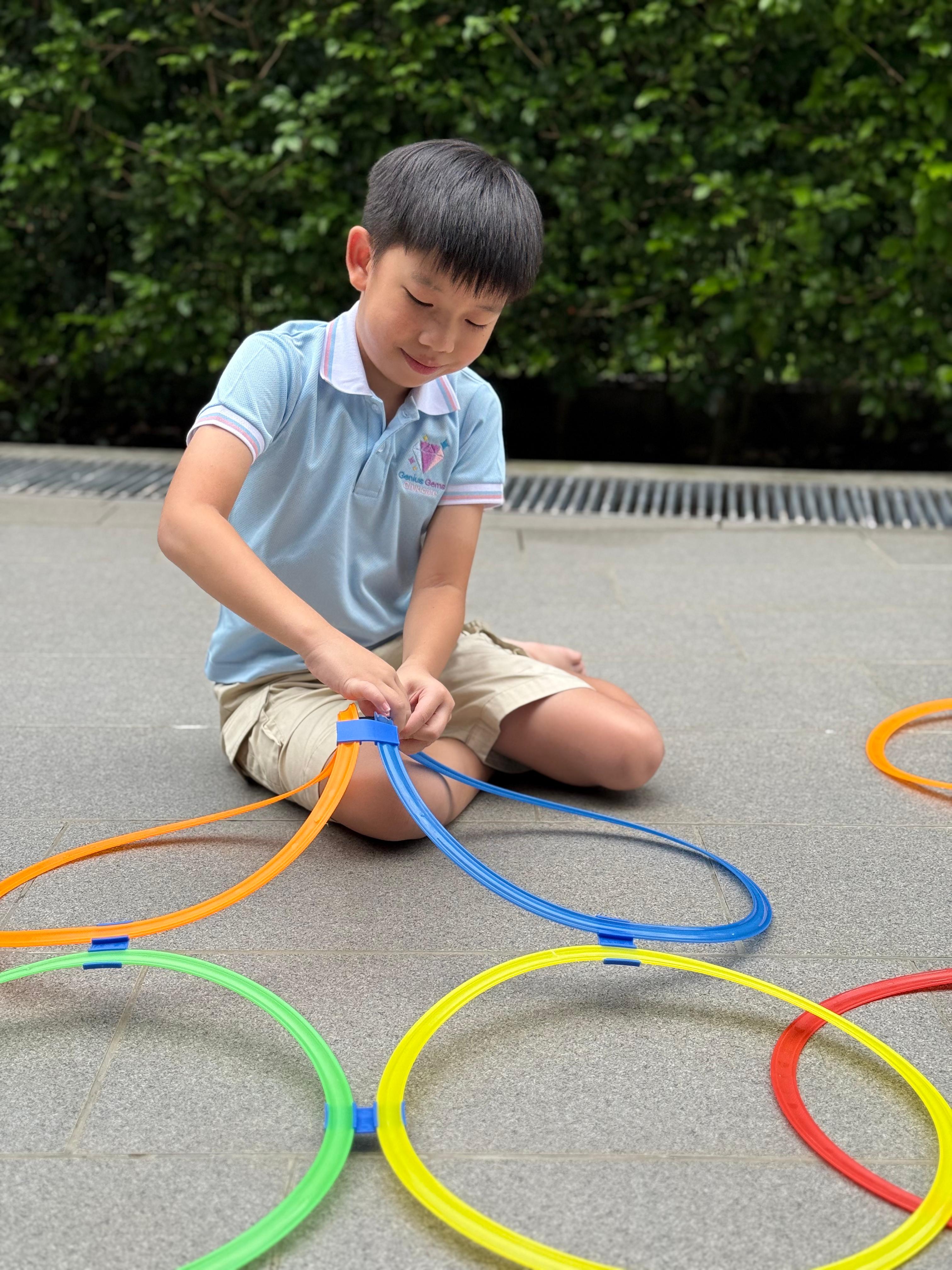 Child playing with colourful rings during a hands-on learning activity at Genius Gems Childcare Centre